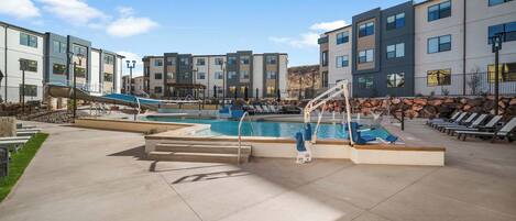 A pool area with a slide, lounge chairs, and a staircase leading to the pool.