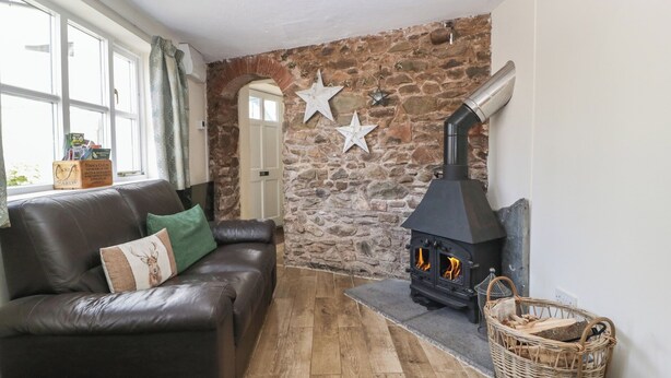 Un salon chaleureux avec un mur en pierre, une cheminée, un canapé en cuir et une fenêtre avec des rideaux.