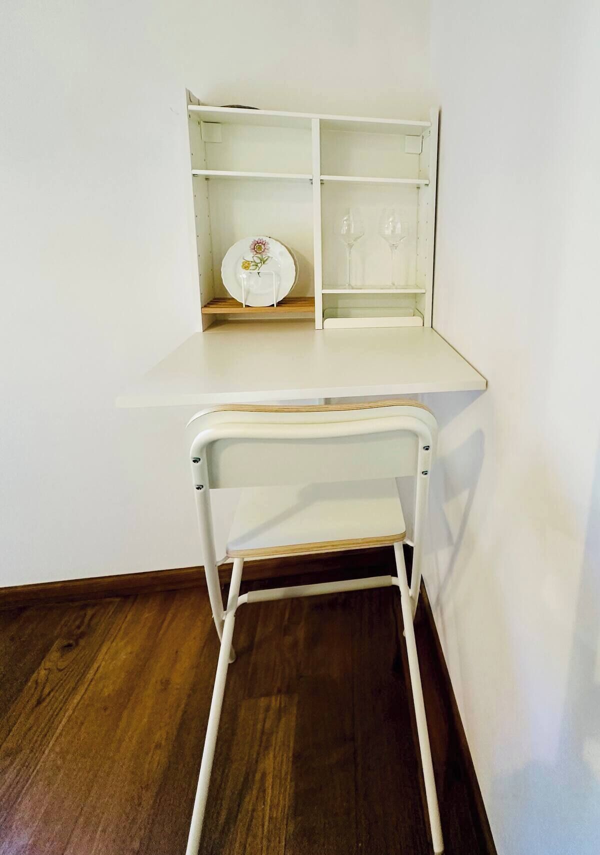 Un bureau blanc doté d’une étagère intégrée et d’une chaise pliante.