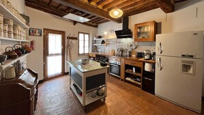 Una cocina rústica con vigas de madera, una isla central y un refrigerador blanco.