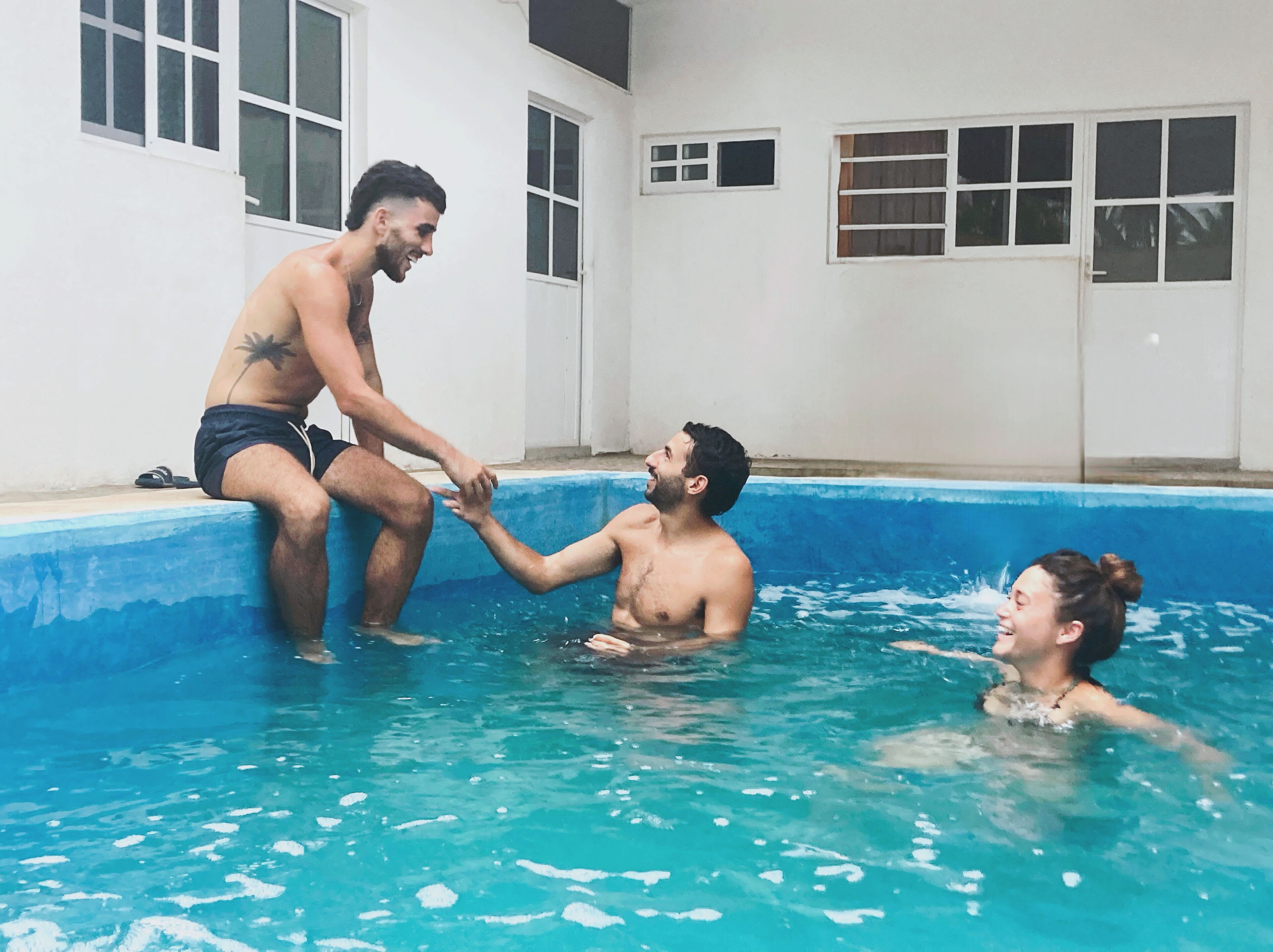 Una piscina con tres personas interactuando.