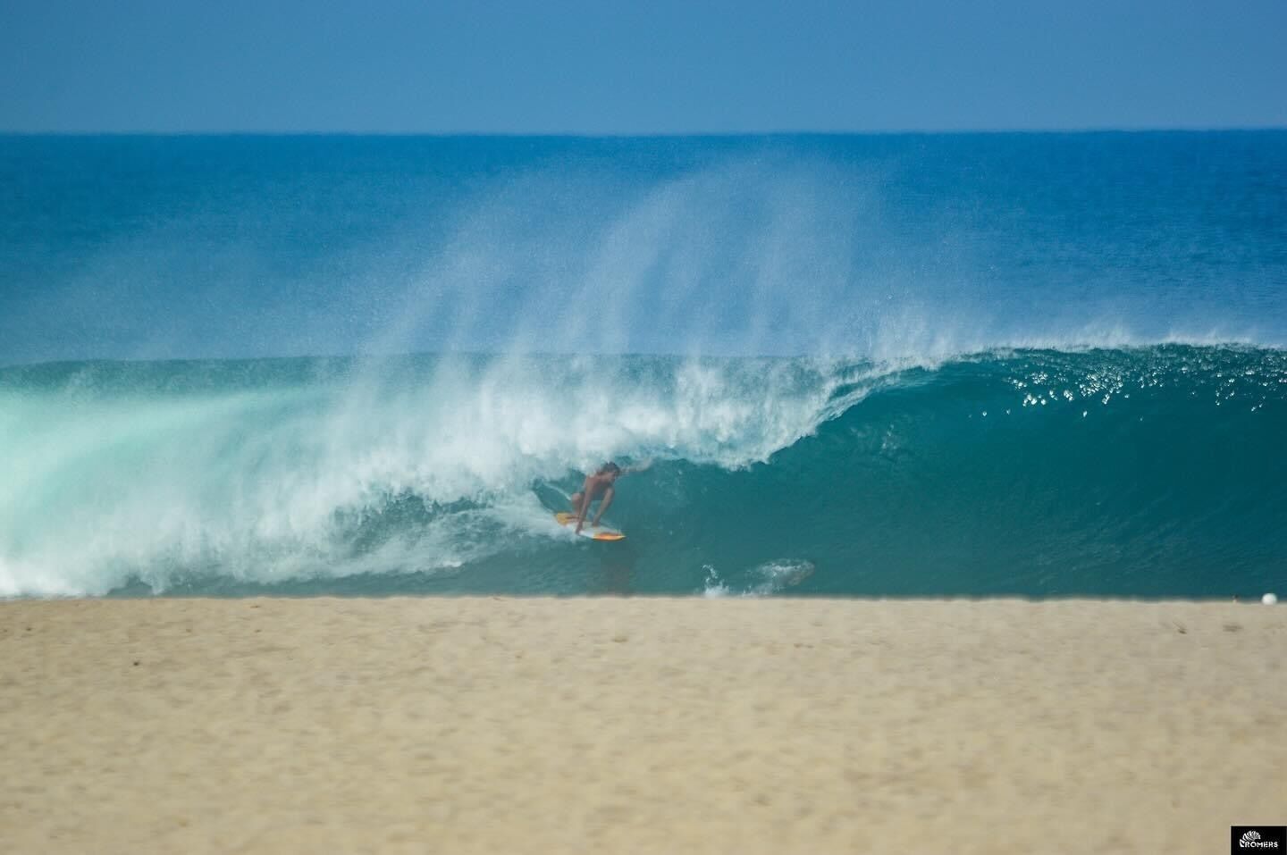 A beach scene with a surfer riding a wave.
