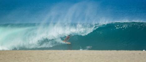 A beach scene with a surfer riding a wave.