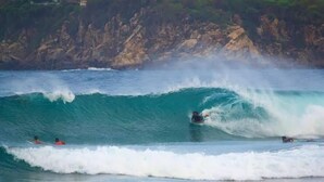 A coastal scene with a large wave and surfers. - Casa PXM Ocean view (Puerto Escondido)