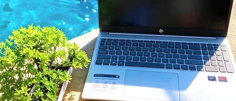 A laptop on a surface with a pool in the background.