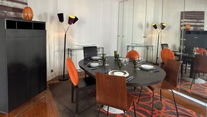 Un coin repas avec une table ronde, des chaises noires et un grand miroir.