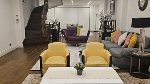 Un salon spacieux comprenant un ensemble de canapés, une table basse et un escalier menant à un autre niveau.