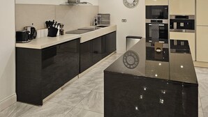 Une cuisine moderne avec un îlot central noir, des appareils en acier inoxydable et un crédence blanche.