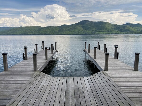 Eine hölzerne Pier, die sich in ruhiges Wasser erstreckt, mit Laternen in regelmäßigen Abständen.