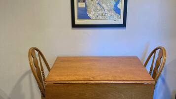 A framed map of Seattle on a wall, a wooden dining table with four chairs, and a small rug on the floor.