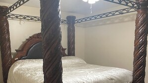 Un lit à baldaquin avec un cadre en bois et un ventilateur de plafond au-dessus.