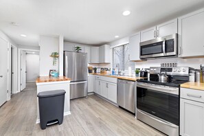 A modern kitchen with stainless steel appliances, white cabinetry, and a wooden countertop. - Abstract Livin Free WiFi & Parking (Overland Park)