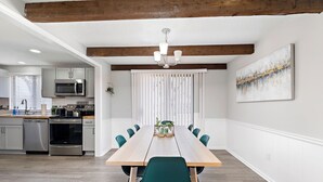 A modern kitchen with stainless steel appliances, a wooden dining table with chairs, and a chandelier. - Overland Park 4BR Home 2 Kings Garage Dog Friendly (Overland Park)