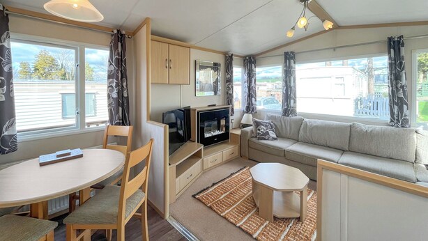 A compact living space with a dining table, chairs, a sofa, a TV, and a small table.