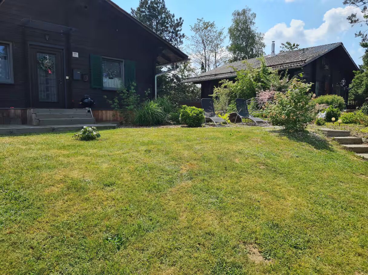 Una casa de madera con césped cuidado y un pequeño jardín.