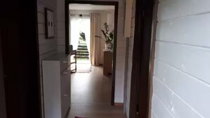 A hallway with a staircase leading to a balcony, a potted plant, and a door on the right. - Holiday cottage near Passau /Pullman City (Windorf)