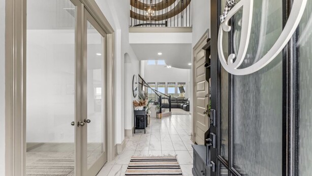 A spacious hallway with a staircase leading to a second floor, a large window, and a modern interior design. - Luxury Retreat w/ Pool & Spa (Katy)