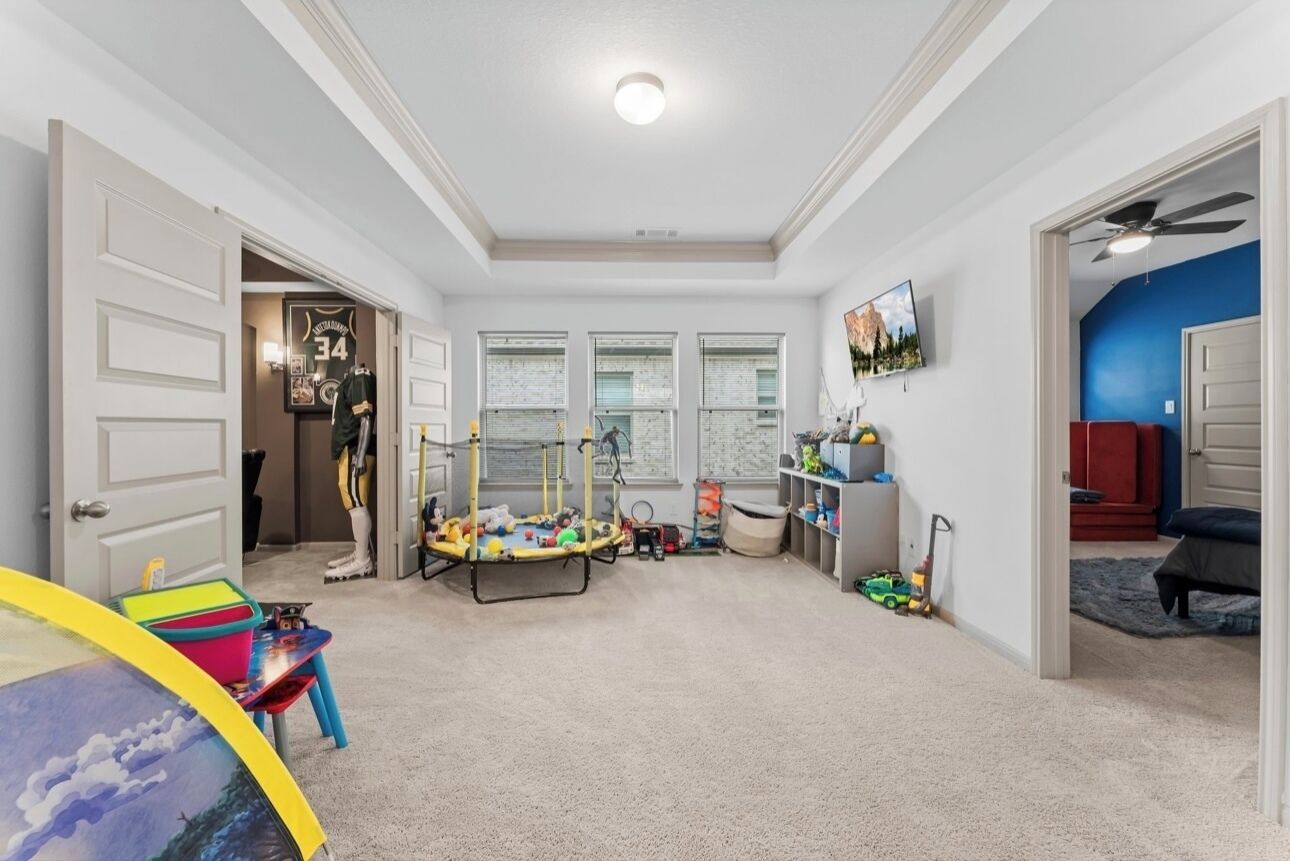 A spacious room with a trampoline, a play area, and a television mounted on the wall.