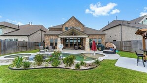A residential house with a backyard featuring a swimming pool, outdoor seating, and a covered patio area. - Luxury Retreat w/ Pool & Spa (Katy)