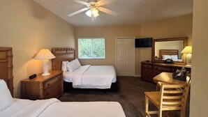 A hotel room with two beds, a desk, a chair, a ceiling fan, a TV, and a window with blinds. - Right Direction Rentals Studio Villa 8229 (Port St. Lucie)