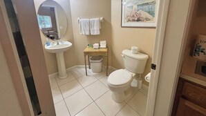 A bathroom with a sink, mirror, toilet, and a framed picture on the wall. - Right Direction Rentals Studio Villa 8229 (Port St. Lucie)