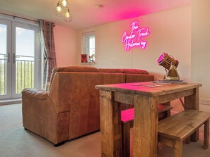 A living room with a sofa, a wooden table, and a neon sign.