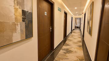 Un pasillo de hotel con puertas, un letrero de salida de incendios y un pasillo que lleva a una habitación.