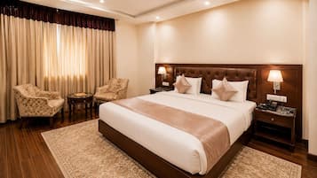 A hotel room with a large bed, two armchairs, a bedside table, and a lamp.