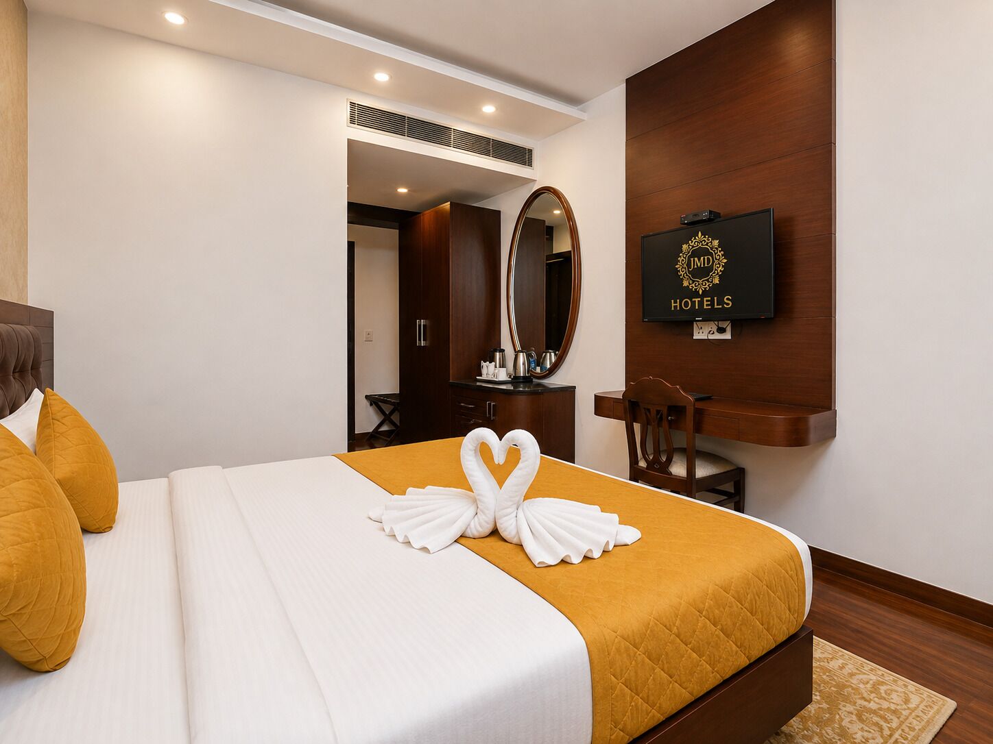 A hotel room with a bed, a desk, a chair, a television, and a mirror.