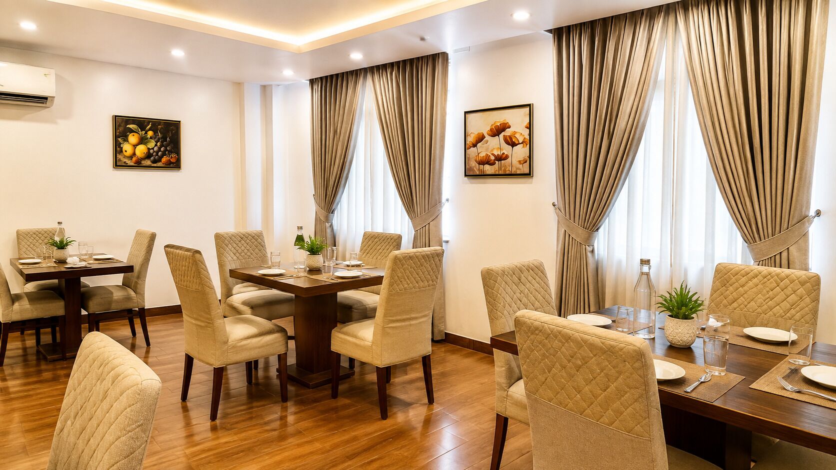 Un comedor de hotel con una mesa central, rodeada de sillas y dos ventanas con cortinas.