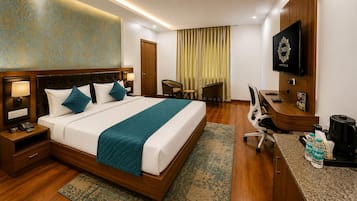 Habitación de hotel con cama, escritorio, silla, televisor y minibar.