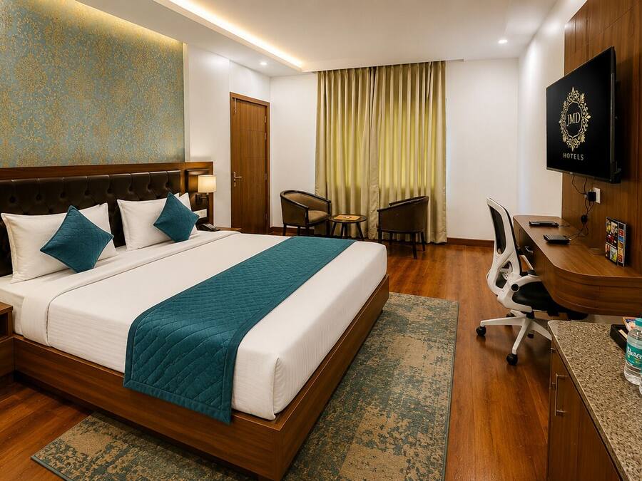 Habitación de hotel con cama, escritorio, silla, televisor y minibar.