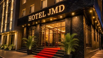 A hotel entrance with a sign reading 'HOTEL JMD,' a red carpet, and a staircase leading to the entrance.