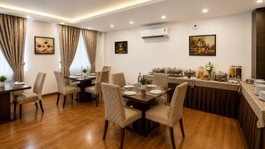 A dining area with a buffet setup, including a table with chairs and a buffet counter with food and drinks. - Hotel JMD - Managed by Kian (New Delhi)