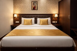 A hotel room with a large bed, two bedside tables with lamps, a wooden headboard, and a patterned wallpaper. - Hotel JMD - Managed by Kian (New Delhi)