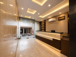 A modern reception area with a marble floor, a reception desk labeled 'RECEPTION,' and a wall-mounted clock.