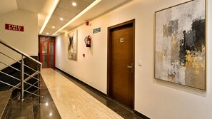 Un couloir d’hôtel avec un panneau indiquant la sortie de secours, un extincteur, une porte portant l’inscription « 309 » et un grand tableau abstrait.