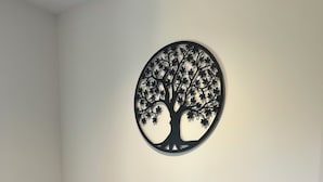 A bedroom with a bed, two pillows, and a wall-mounted tree decoration. - Le Mas d'Archas (Allan)