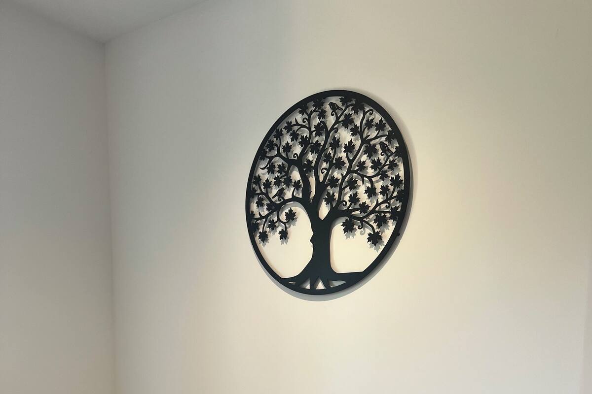 A bedroom with a bed, two pillows, and a wall-mounted tree decoration.
