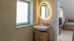 A bathroom with a window, a sink, and a mirror.