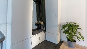 A narrow hallway with a potted plant, a window with curtains, and a door.