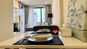 Ein Hotelzimmer mit Essbereich, einem Flachbildfernseher, einem Vogelgemälde und einer herzförmigen Dekoration auf dem Tisch.