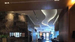 Eine moderne Lobby mit einer geschwungenen Treppe, einem Korbsessel und einer Steinwand.
