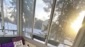 Un coin salon confortable offrant une vue sur un paysage enneigé grâce à de grandes fenêtres.