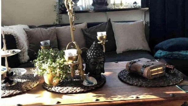 Un salon chaleureux avec un canapé, des objets de décoration et une fenêtre agrémentée de rideaux.