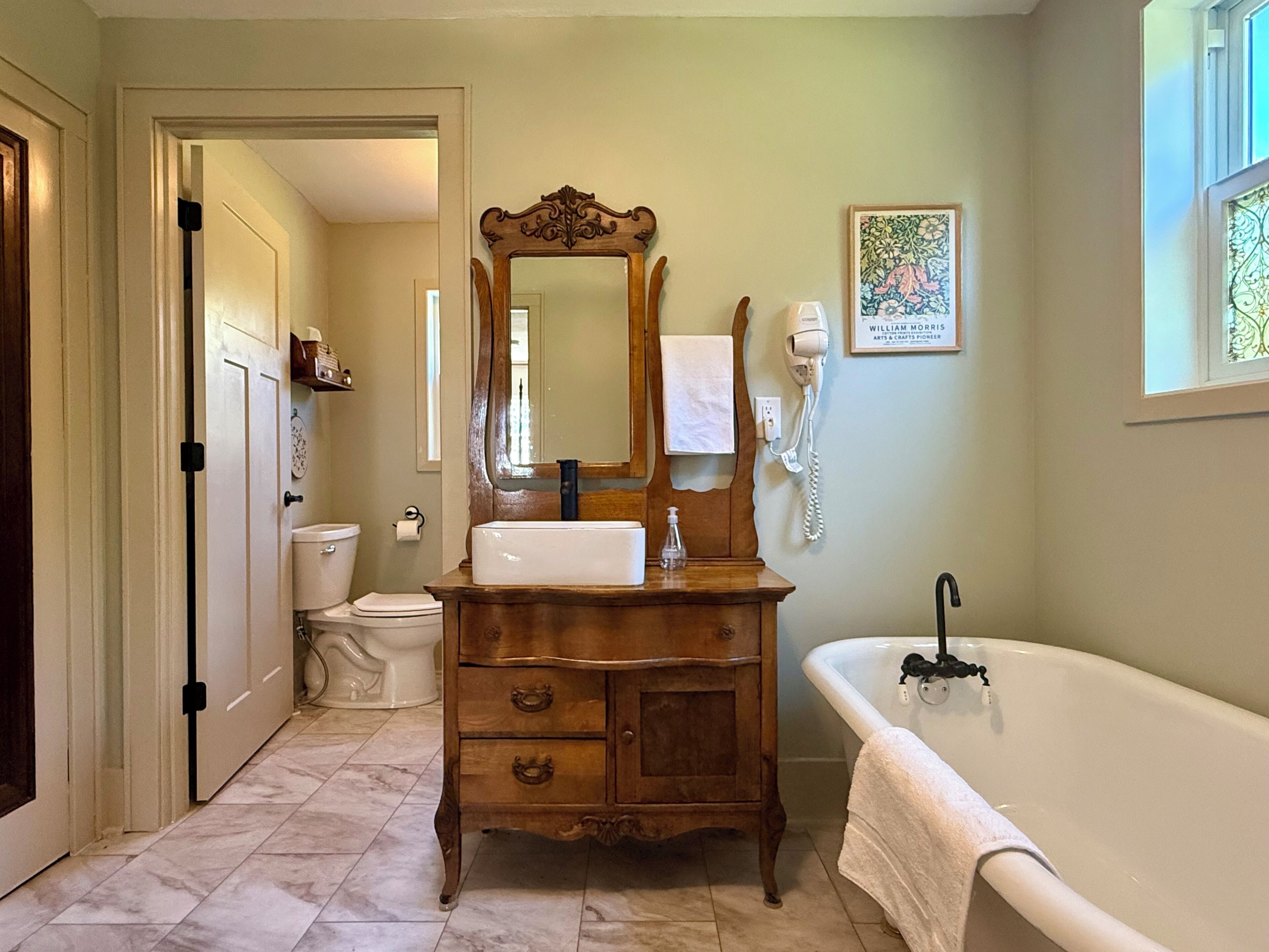 Une salle de bain avec un meuble-lavabo en bois, un lavabo blanc, un grand miroir, des toilettes blanches et une baignoire.