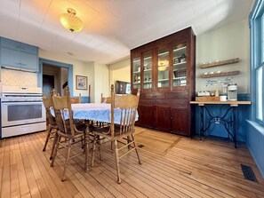 Un comedor con mesa y sillas de madera, una cocina con estufa y armarios, y una ventana con vistas.