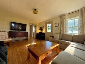 Una sala de estar con una mesa de centro de madera, un sofá, un televisor y un piano.