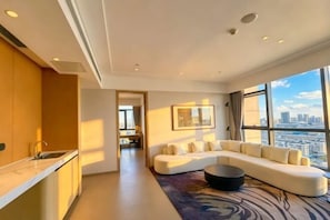 A modern living room with a large window, a sofa, and a kitchen area.
