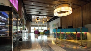 A modern hotel lobby with a reception desk, colorful seating, and a marble floor. - Yancheng Baolong Yiyue Select Hotel (Yancheng)
